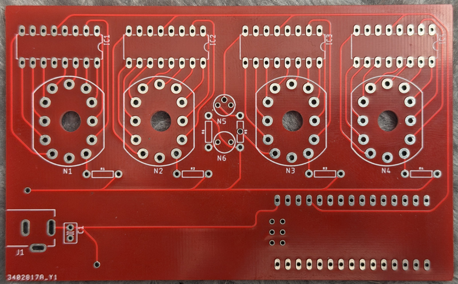 A red circuit board with positions for four digit nixie tubes, two dot nixie tubes, and four BCD decoders, as well as an Arduino Nano.